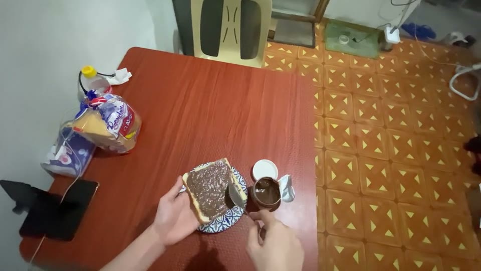 First-person view of two hands assembling a sandwich on a table.