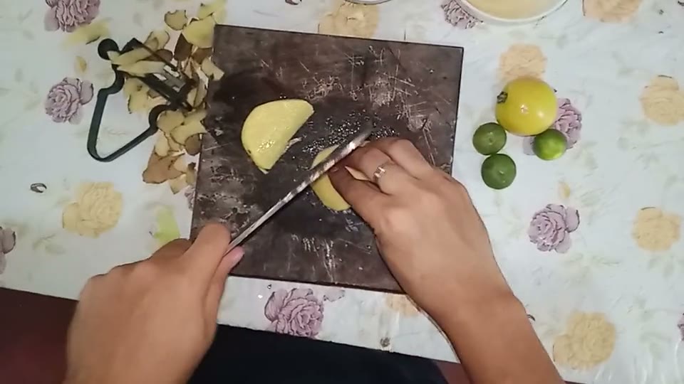 First-person view of two hands cutting a vegetable on a small chopping board.